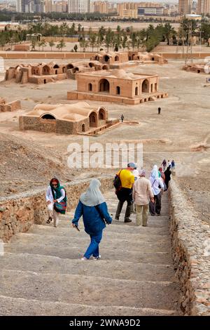 Touristen gehen eine Steintreppe hinunter, nachdem sie den Turm der Stille (Dakhmeh) besucht haben, eine Struktur, die in der zoroastrischen Begräbnistradition verwendet wurde. Yazd, Iran. Zoroast Stockfoto