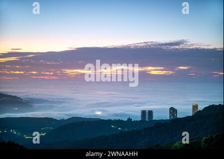 Wolken und Nebel ziehen über die Stadt, und das bunte glasierte Licht leuchtet. Genießen Sie den Sonnenuntergang und das Wolkenmeer. Zhongzhengshan Wander Trail, Taipeh Stadt Stockfoto