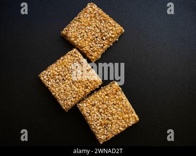 Bis Chikki auf schwarzgrauem Hintergrund. Till Chikki ist ein indisches Süßwarengericht, das mit Jaggery und Sesam zubereitet wird. Indisches Festival makar sankranti besonderes Süßes Stockfoto