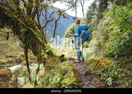 Junge Frau mit Rucksack und Stangen Trekking Walking Mera Peak Kletterroute durch Dschungel Regenwald im Makalu Barun Nationalpark, Nepal. Aktiv Stockfoto