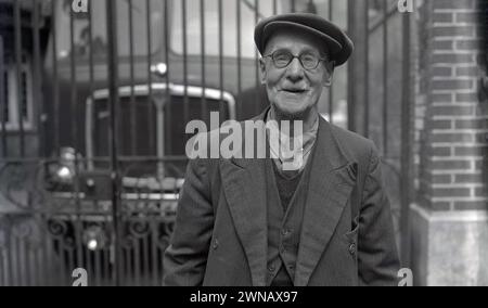 1950er Jahre, historisches Foto, das Bill Baker zeigt, einen langjährigen Mitarbeiter mit 60 Jahren treuer Arbeit, der an den Werkstoren seines ehemaligen Arbeitgebers Lucys, Oxford, England, Großbritannien, stand. Das Geschäft von W. Lucy & Co stammt aus dem Jahr 1812, als William Carter ein Eisenwarengeschäft an der Oxford High Street eröffnete. 1825 zog es in eine neue Messing- und Eisengießerei in Jericho, Oxford, die später als Eagle Works bekannt war. Stockfoto