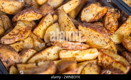 Kartoffelecken, geröstete Backofen mit Thymian, Nahaufnahme von oben in ein Backblech auf einem dunklen Holzmöbeln im Landhausstil Hintergrund Stockfoto