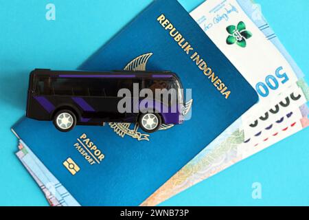 Blauer Indonesien-Pass mit Geld und Spielzeugbus auf blauem Hintergrund Nahaufnahme. Tourismus und Reisekonzept Stockfoto