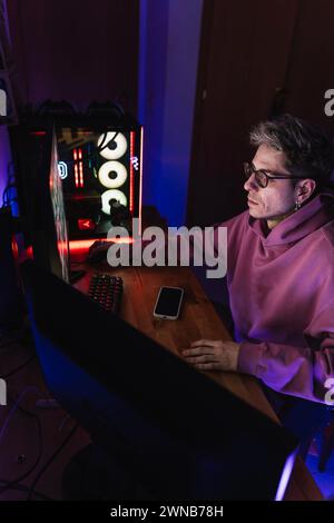 Junger Mann, der Videospiele in seinem dunklen Zimmer spielt. Stockfoto