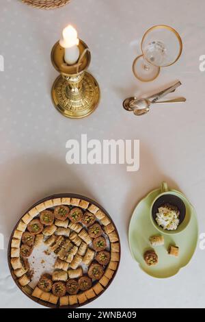 Trinken Sie Schokolade mit Sahne und Pistazien in passender grüner Tasse und Teller mit verschiedenen Baklava-Dessertdosen auf dem Tisch Stockfoto