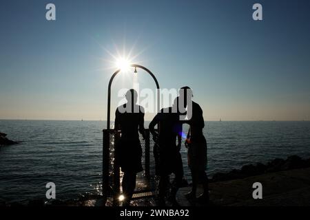 Drei Männer stehen unter einer Dusche und küssen sich gegenseitig Stockfoto