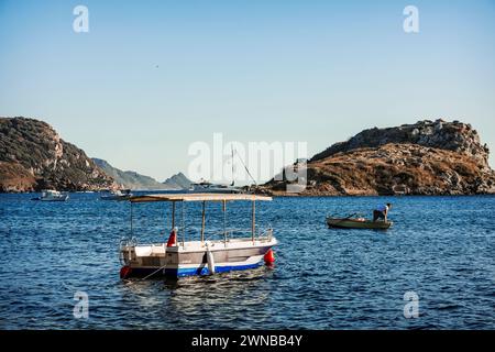 Boote, die bei Sonnenuntergang in den ruhigen Gewässern der Gumusluk Bay ankern, einem Fischerdorf unweit von Bodrum Stockfoto