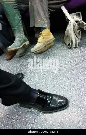 Ein Mann sitzt auf einer Bank mit hochgezogenen Füßen und einer Tasche auf dem Schoß Stockfoto