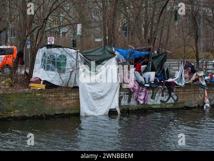 Berlin, Deutschland. Januar 2024. 15.01.2024, Berlin. Obdachlose haben sich trotz der winterlichen Temperaturen aus Plastikfolien, Müll und den Überresten eines alten Hauszelt am Ufer des Landwehrkanals einen provisorischen Unterschlupf gebaut. In der Hauptstadt gibt es nun immer mehr solche informellen Zeltgebäude und Hütten. Obdachlose Alkoholiker oder mehrfache Süchtige aus Osteuropa leben in vielen von ihnen ohne Strom, fließendes Wasser oder Kanalisation, oft monatelang. Kredit: Wolfram Steinberg/dpa Kredit: Wolfram Steinberg/dpa/Alamy Live News Stockfoto