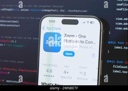 New York, USA - 23. Februar 2024: Zoom auf iphone-Bildschirm mit unscharfem Code-Programmierhintergrund Stockfoto