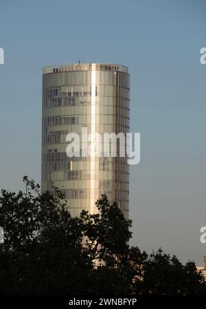 Das Koln-Dreieck-Gebäude, ehemals LVR-Turm genannt, vor einem klaren blauen Himmel am späten Nachmittag mit einigen Bäumen im Vordergrund. Stockfoto