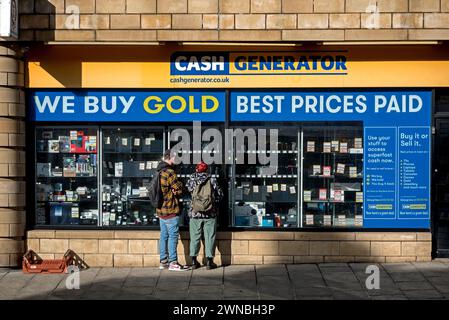 Ein junges Paar, das in das Fenster von Cash Generator schaut, einem Kaufen- und Verkaufsgeschäft an der Dalry Road, Edinburgh, Schottland, Großbritannien. Stockfoto