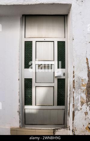 Aluminium- und Glastür an abgesplitterter Fassade in Elvas, Portugal Stockfoto