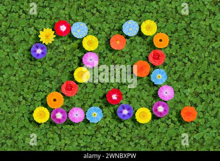 Nummer geschrieben mit bunten Blumen auf grünem Kleeblatt Hintergrund Stockfoto