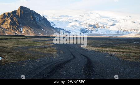 Straße in Südisland Island im Winter mit schneebedeckten Bergen bei Myrdalsjökull und blauem Himmel im Hintergrund Stockfoto