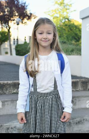 Ein Mädchen in Schuluniform und Rucksack kehrt zur Schule zurück Stockfoto