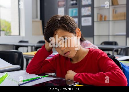 Ein birassischer Junge mit braunen Haaren sieht traurig aus in der Schule Stockfoto