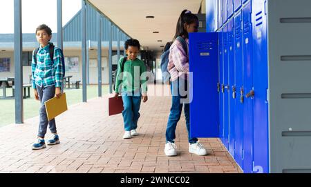 Biracial Boy und Afroamerikaner gehen an einem Biracial Mädchen in den Schulschließfächern vorbei Stockfoto