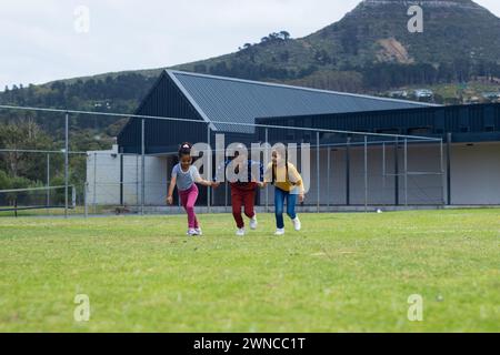 Drei rassistische Mädchen spielen auf einem Grasfeld in der Schule, mit Kopierraum Stockfoto