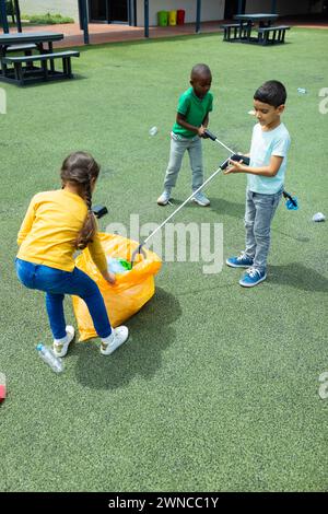 Die Kinder nehmen auf einem Schulspielplatz Müll mit Greifern auf Stockfoto