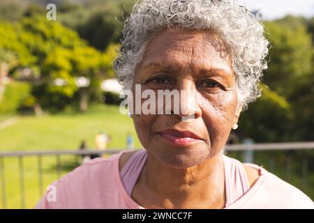 Ältere Frau mit grauen Haaren und warmbraunen Augen steht draußen Stockfoto