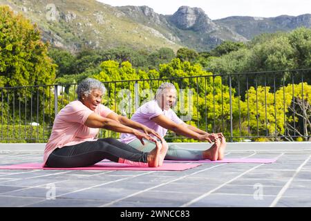 Ältere afroamerikanische Frauen und ältere birassische Frauen lächeln beim Yoga im Freien Stockfoto