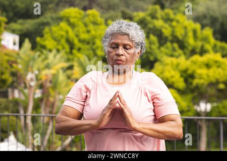 Ältere birassische Frau mit grauem Haar übt Yoga im Freien Stockfoto