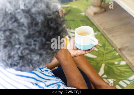 Eine ältere afroamerikanische Frau mit grauem Haar genießt zu Hause eine Tasse Tee Stockfoto