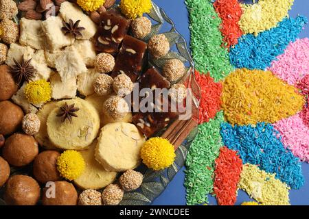 Diwali-Feier. Leckere indische Süßigkeiten, Gewürze, Nüsse und bunte Rangoli auf blauem Tisch, flache Lay Stockfoto