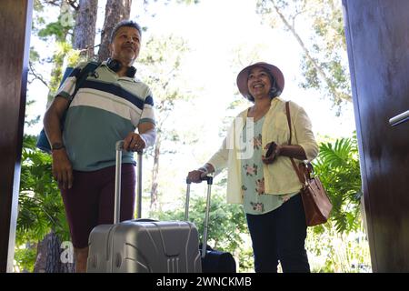 Seniorenpaar in lässiger Reisekleidung, bereit für eine Reise, mit Gepäck in der Hand Stockfoto