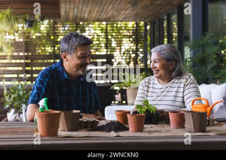 Ein hochrangiges birassisches Paar genießt es, gemeinsam zu gärten, umgeben von Töpfen und Pflanzen Stockfoto