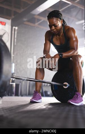 Eine starke, fitte birassische Frau bereitet sich darauf vor, eine Langhantel im Fitnessstudio mit Kopierraum zu heben Stockfoto