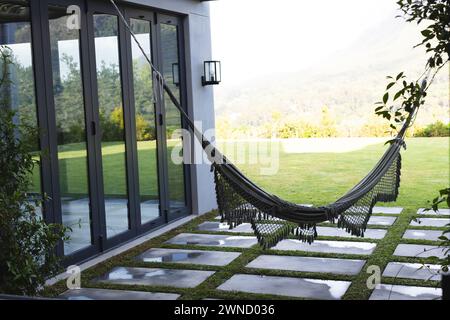 Eine schwarze Hängematte hängt einladend im Hinterhof eines modernen Hauses mit Kopierraum Stockfoto