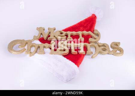 Weihnachtshintergrund mit weihnachtsmütze und goldenem Text für frohe Weihnachten Stockfoto