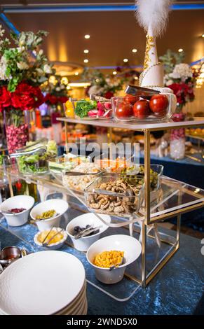 Genießen Sie eine köstliche Auswahl an Salaten, Gemüse und Snacks, die kunstvoll auf einem Buffet-Tisch präsentiert werden. Perfekt für Veranstaltungen, Partys oder Versammlungen. Iso Stockfoto