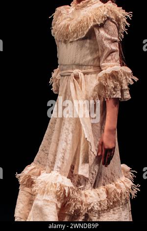 Langes Vintage-Kleid für Kinder in Beige mit Rüschen und Gürtel. Elegante Mode für Mädchen Stockfoto