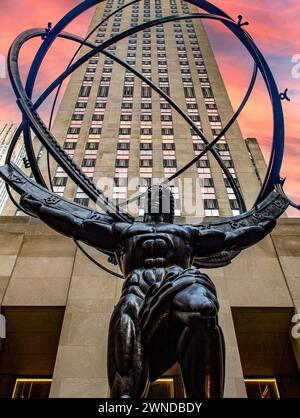 Vertikales Foto des Atlas eine Bronzestatue mit Rockefeller Center im Hintergrund bei Sonnenuntergang oder Sonnenaufgang, im Innenhof des International Stockfoto