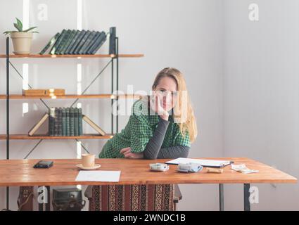 Eine junge hübsche Dame freut sich mit einem lustigen Lächeln vor dem Hintergrund einer Arbeitsumgebung und legt Geld auf. Stockfoto