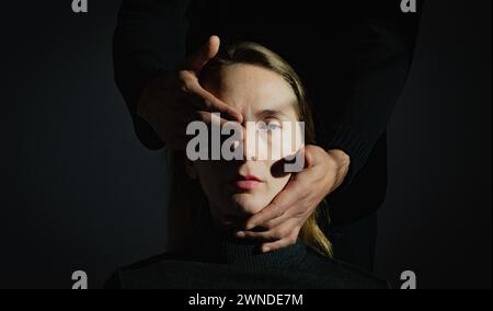 Visualisierung eines psychologischen Problems. Medizinische Themen. Schwierigkeiten des gegenseitigen Verständnisses. Ein Mann hält den Kopf einer erwachsenen jungen Frau in seinem Ha Stockfoto