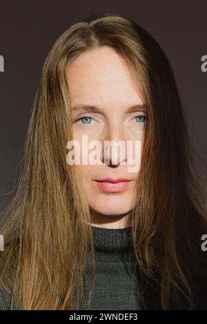 Vertikale Zusammensetzung. Porträt einer erwachsenen jungen Frau mit langen blonden Haaren und grauen Augen in den hellen Sonnenstrahlen. Stockfoto