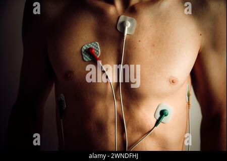 Herzmonitor, EKG, Kardio-Aufzeichnung auf dem Körper eines jungen Mannes. Ein medizinisches Instrument zur Überwachung der Herzfrequenz und der allgemeinen Herzgesundheit. Elektrokarte Stockfoto