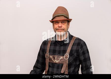 Mann in Tiroler Hut mit Feder und Ledershorts auf weißem Hintergrund. Stockfoto