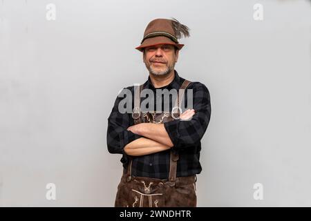 Mann in Tiroler Hut mit Feder und Ledershorts auf weißem Hintergrund. Stockfoto