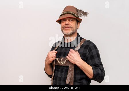 Mann in Tiroler Hut mit Feder und Ledershorts auf weißem Hintergrund. Stockfoto