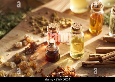 Flaschen ätherischer Aromatherapie-Öle mit Weihrauch, Myrrhe, Zimt und getrockneten Kräutern Stockfoto