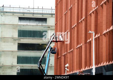 Bauarbeiter auf Hochplattformen, die die Fenster vervollständigen Stockfoto