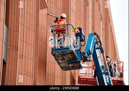 Bauarbeiter auf Hochplattformen, die die Fenster vervollständigen Stockfoto