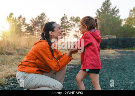 Mutter und Tochter teilen einen liebevollen Moment während einer Wanderung bei Sonnenuntergang, die die Bindung der Familie in der Ruhe der Natur zum Ausdruck bringt. Stockfoto