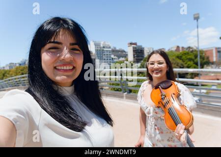 Selfie-Foto von venezolanischer Latina-Touristenfrau, die auf der Straße in venezuela steht, mit einer Geigerin auf der Straße lächelnd in die Kamera schauend, Stockfoto