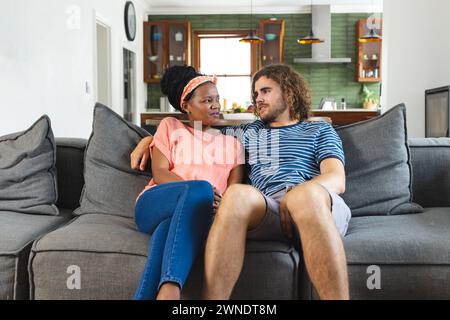 Verschiedene Paare sitzen dicht auf einem grauen Sofa und teilen einen Moment der Zuneigung Stockfoto